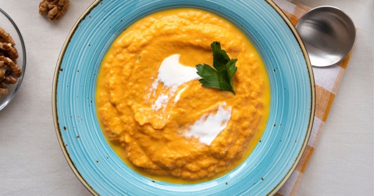 Bowl of smooth puréed carrot soup with a spoon in Leederville