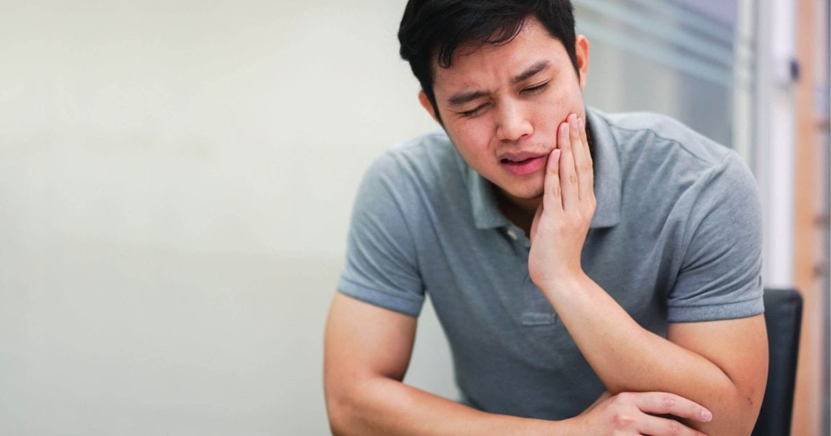 Person experiencing dental pain requiring emergency dentist in Perth